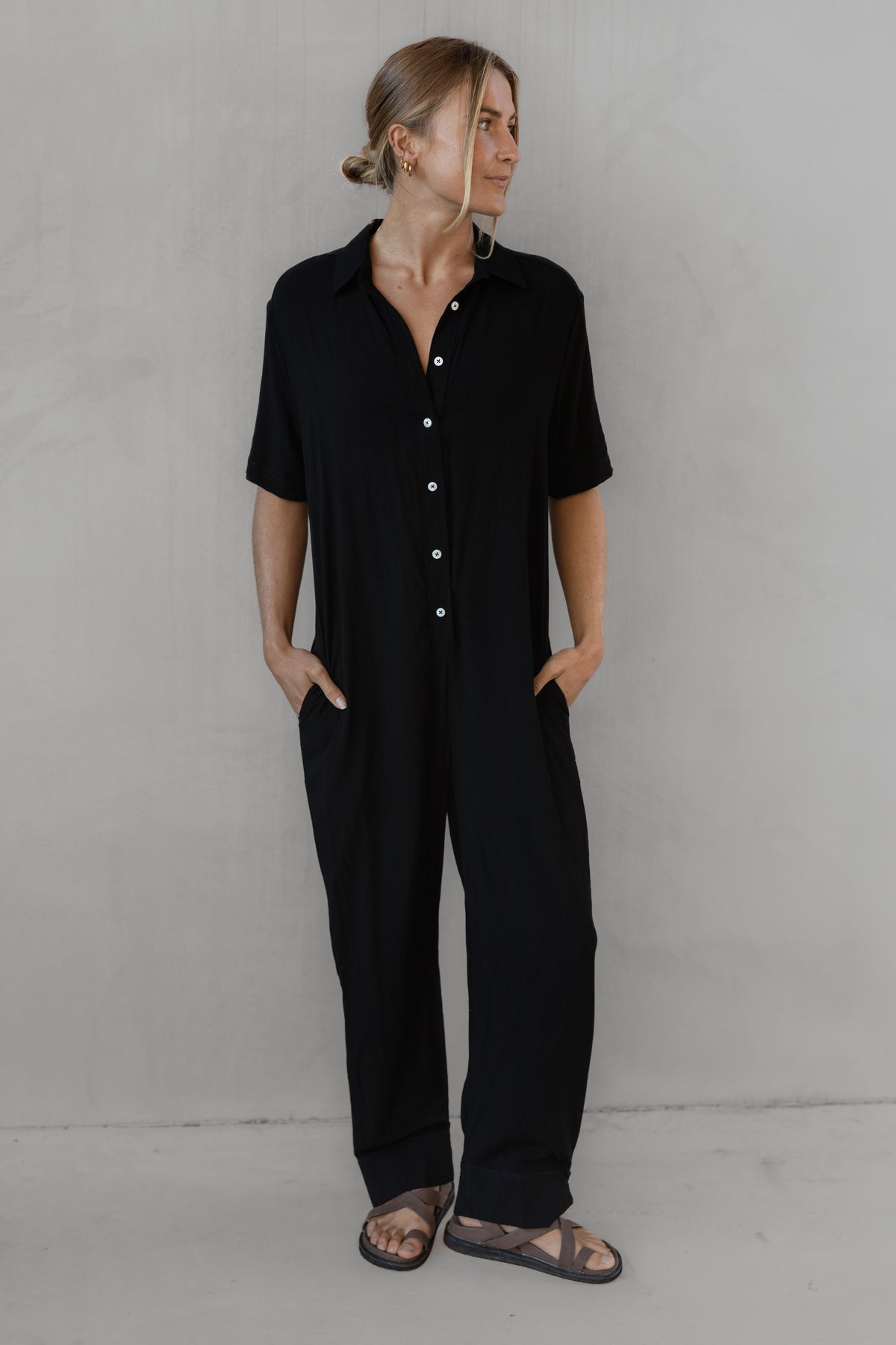 Person wearing a black outfit against a gray background