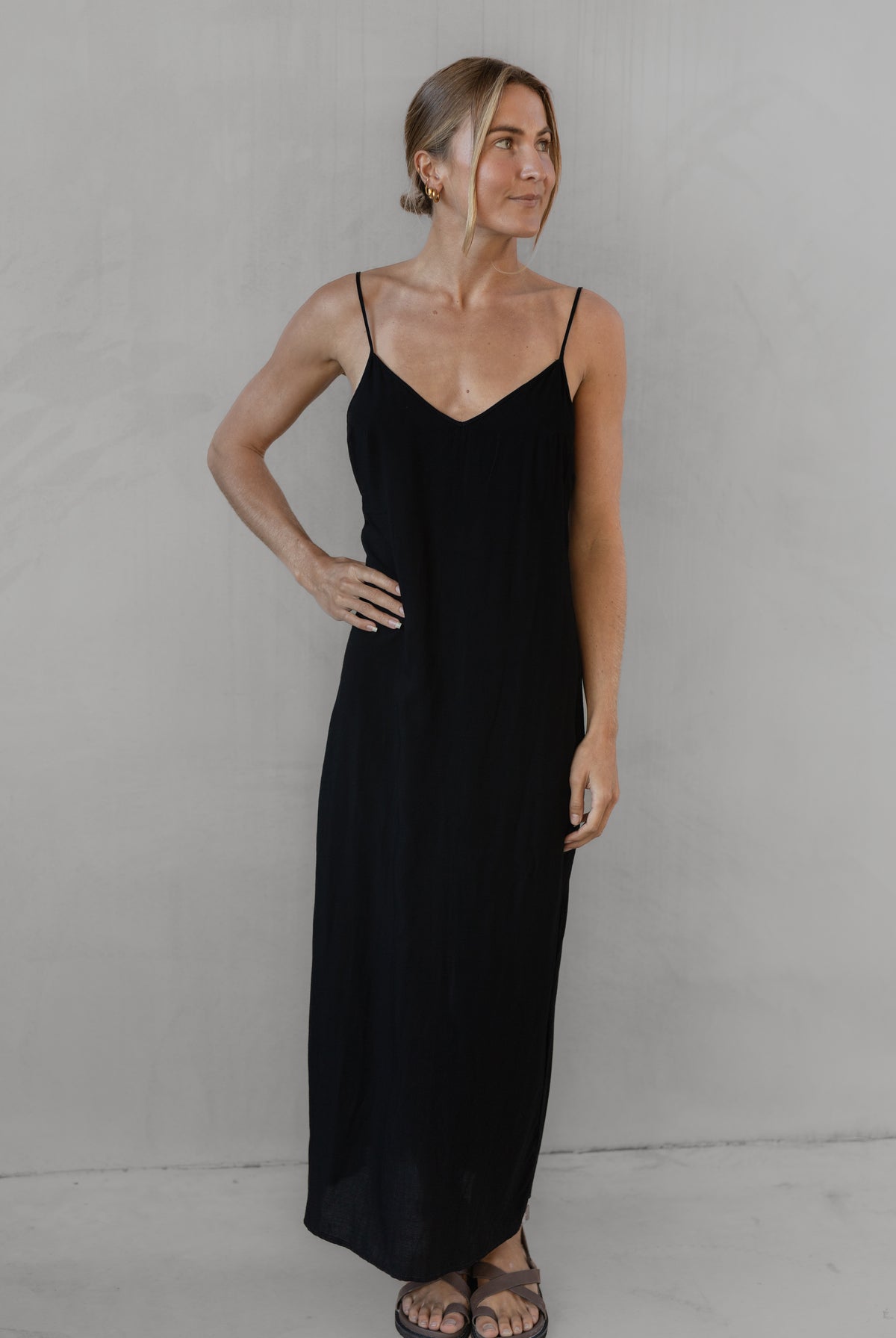 Woman wearing a long black dress with thin straps