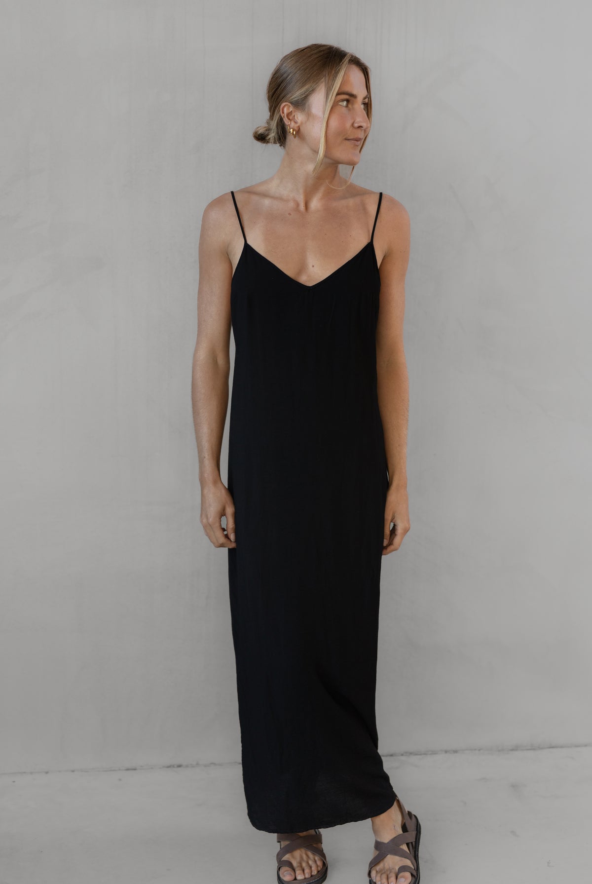 Woman wearing a long black dress with thin straps