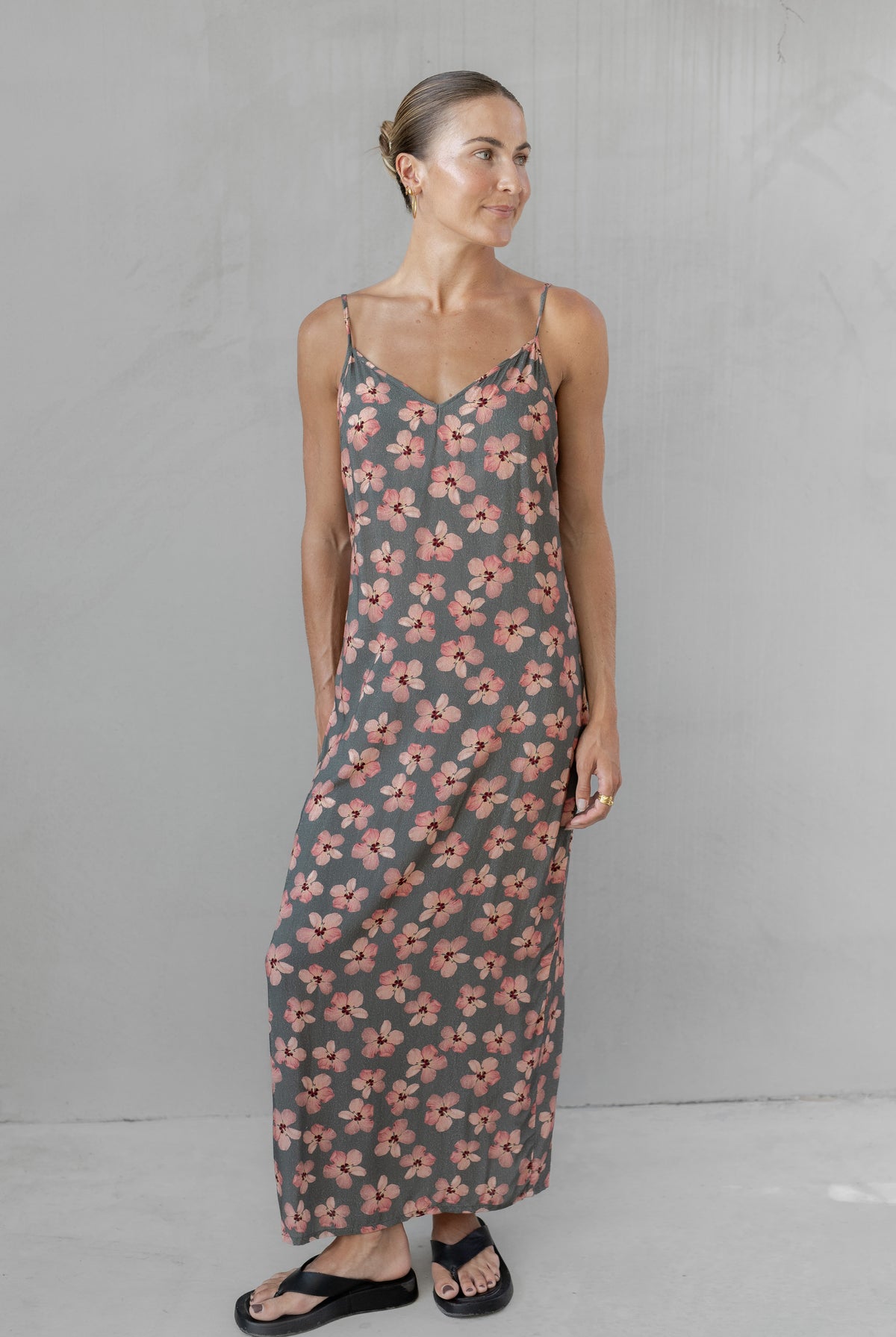 Woman wearing a floral slip dress against a plain background