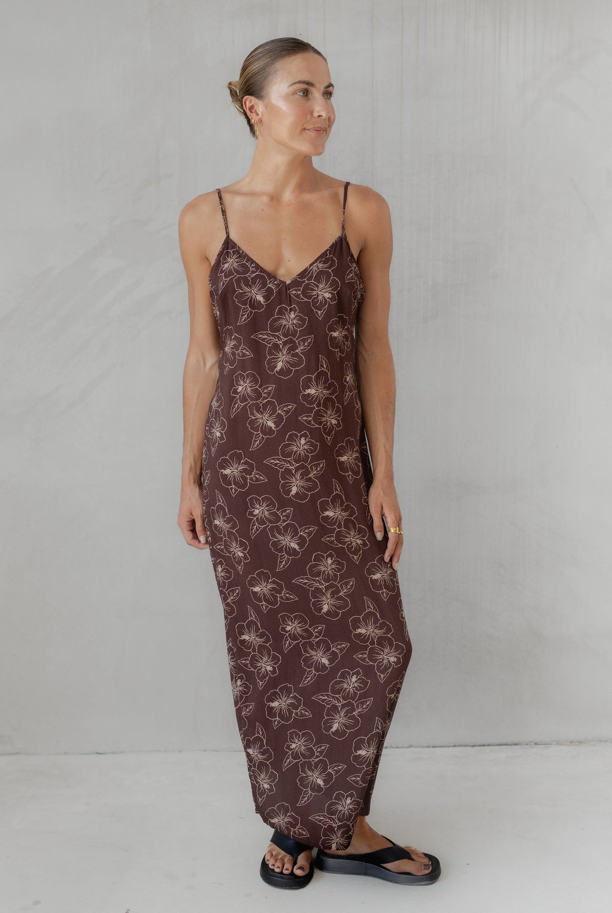 Woman wearing a brown slip dress with floral pattern against a plain background
