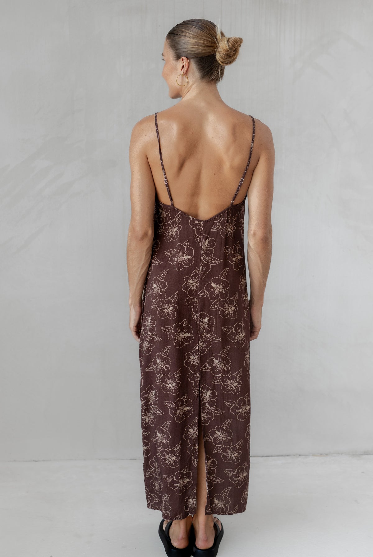 Woman wearing a brown slip dress with a subtle pattern on a plain background