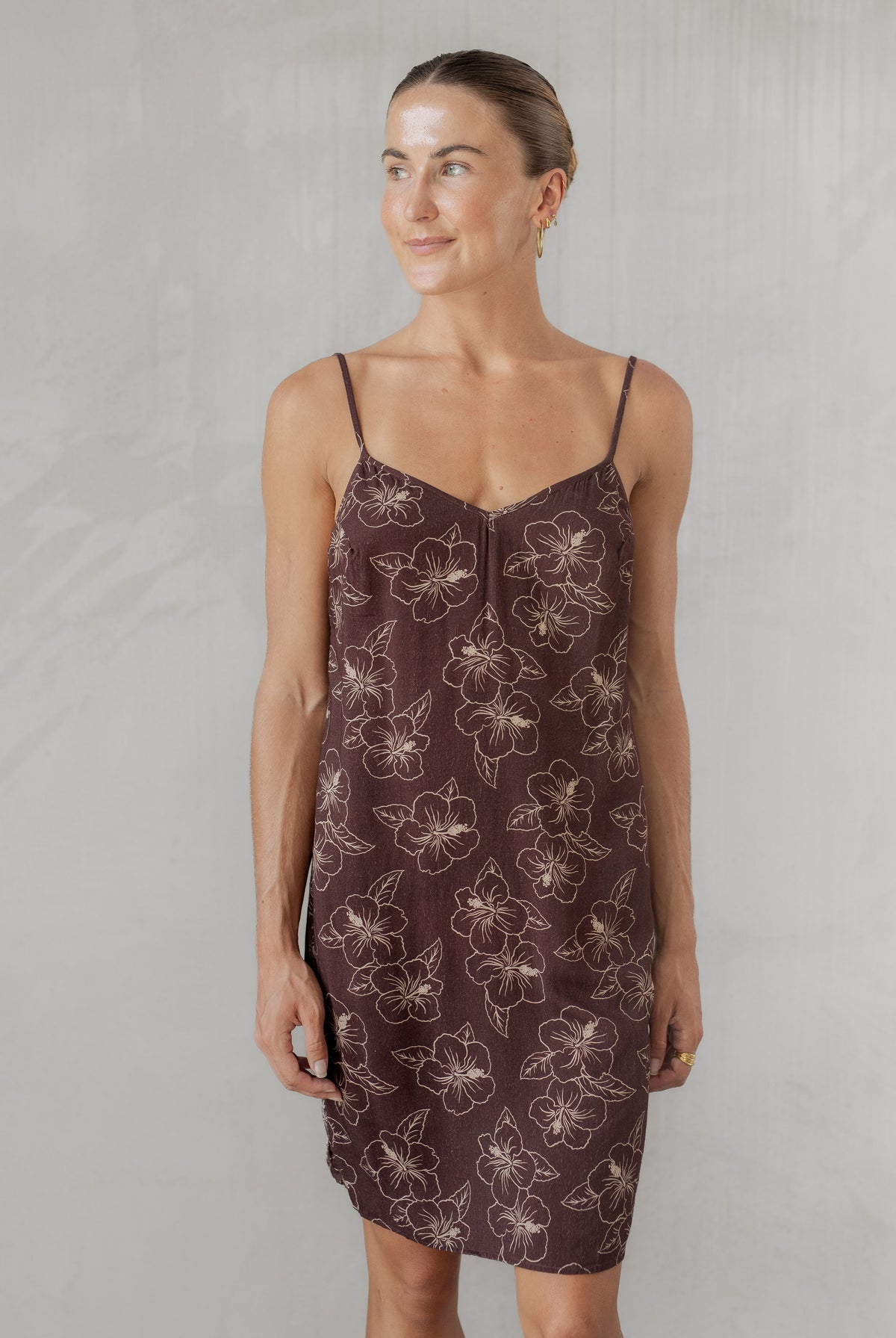 Woman wearing a brown patterned slip dress against a plain background
