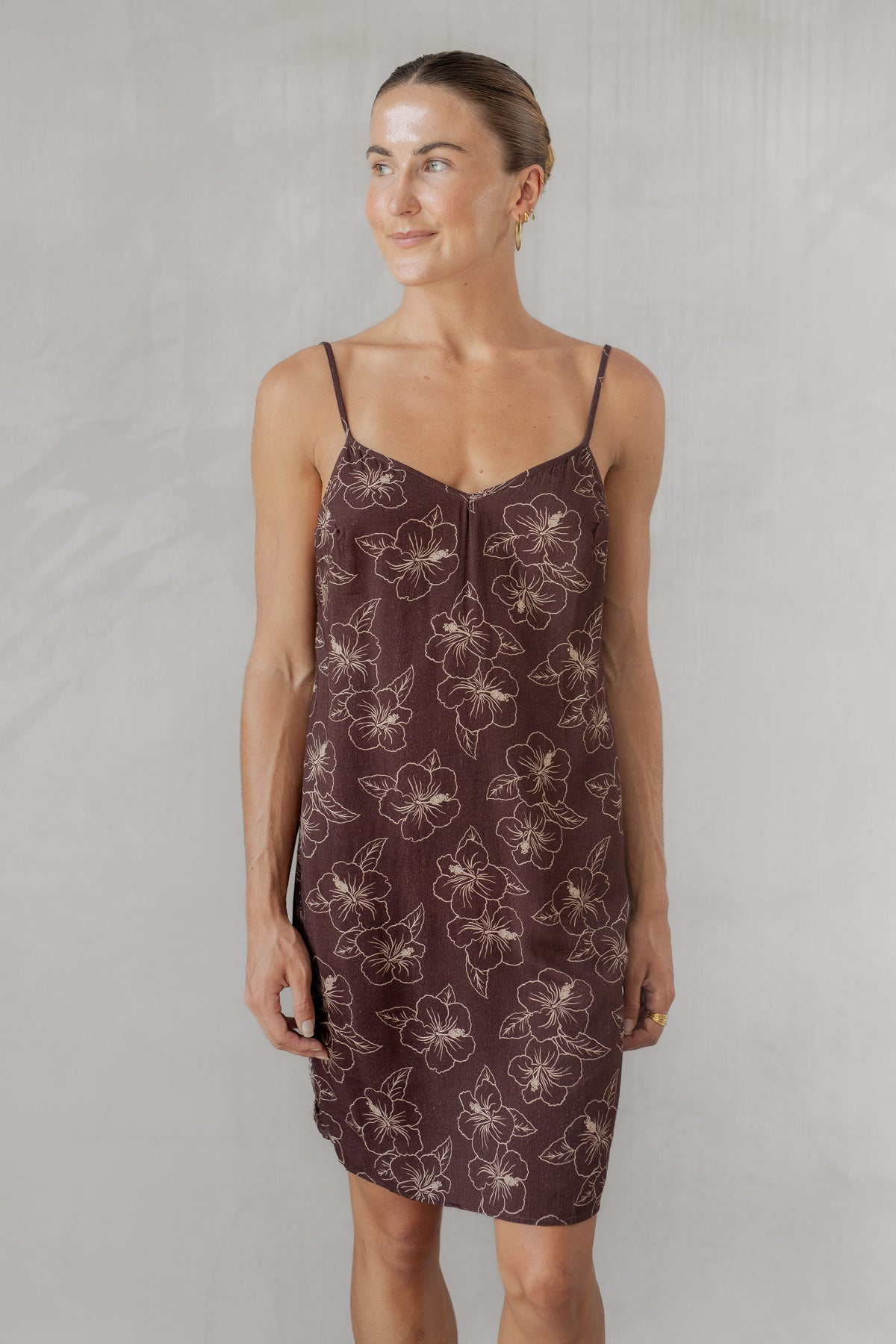 Woman wearing a brown patterned slip dress against a plain background