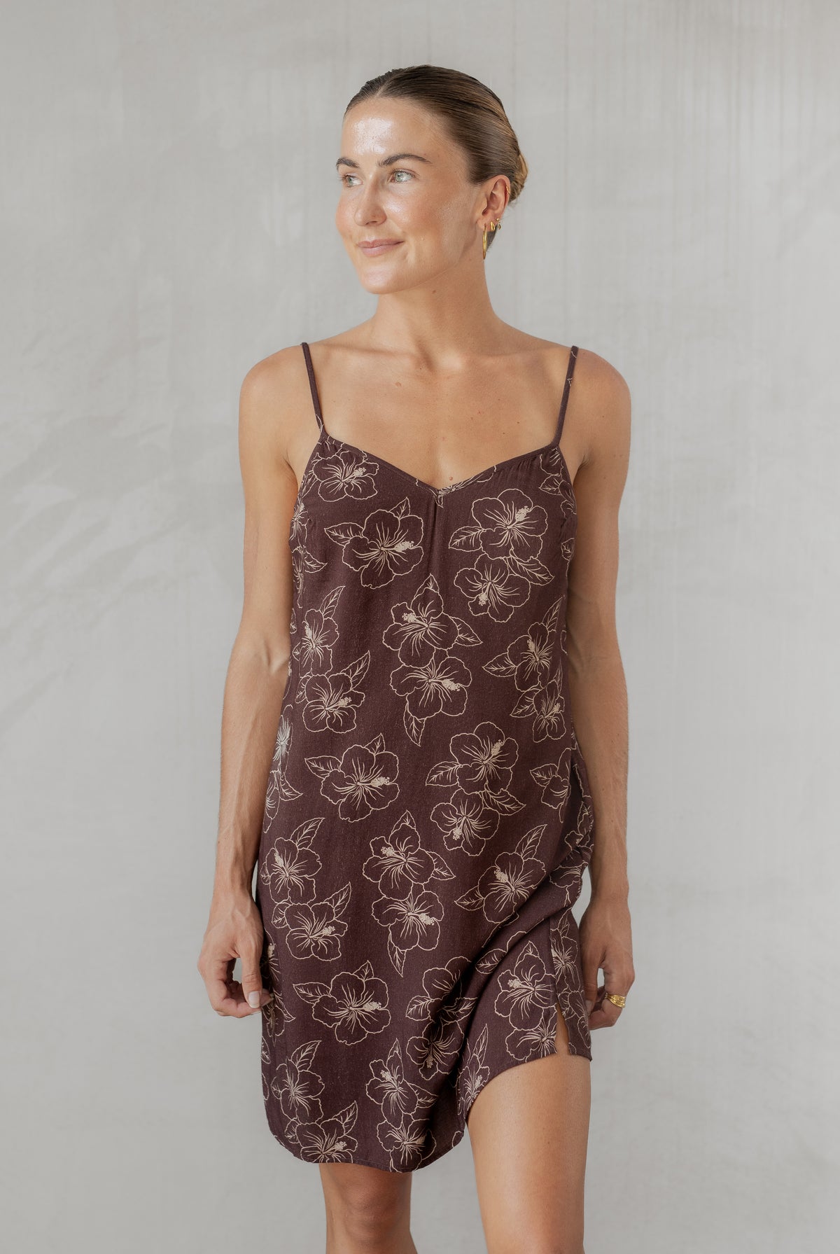 Woman wearing a brown floral slip dress against a plain background