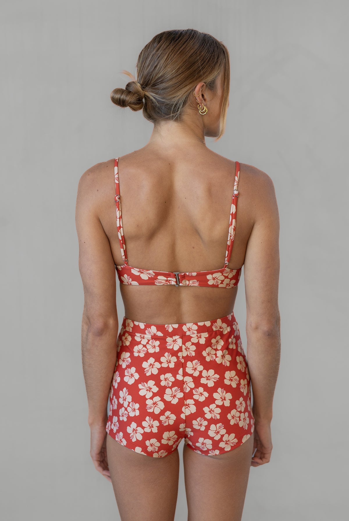 Woman wearing a red floral two-piece swimsuit against a gray background