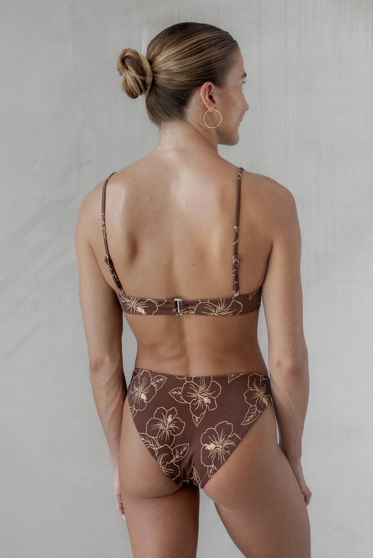 Woman wearing a brown floral bikini against a plain background