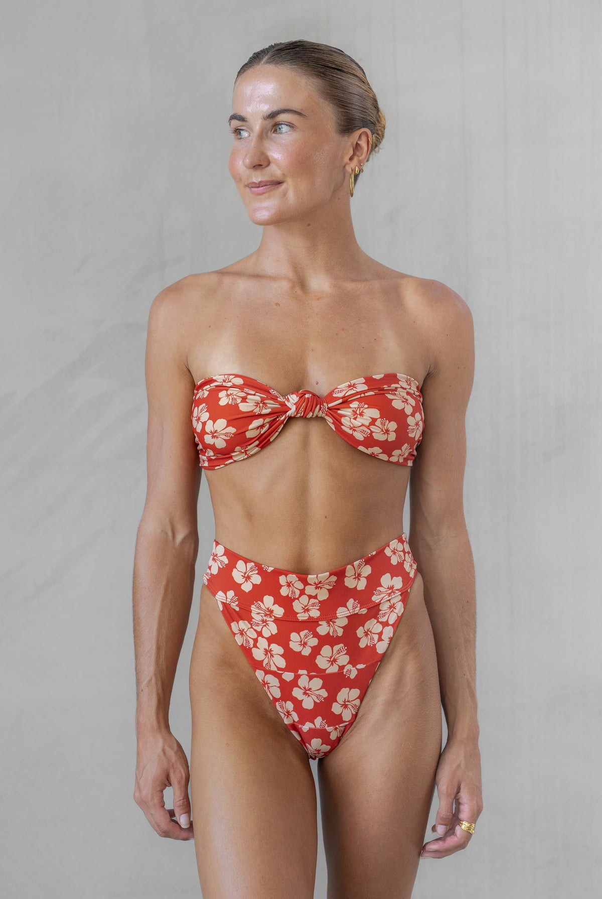 Woman wearing a red floral bikini against a plain background
