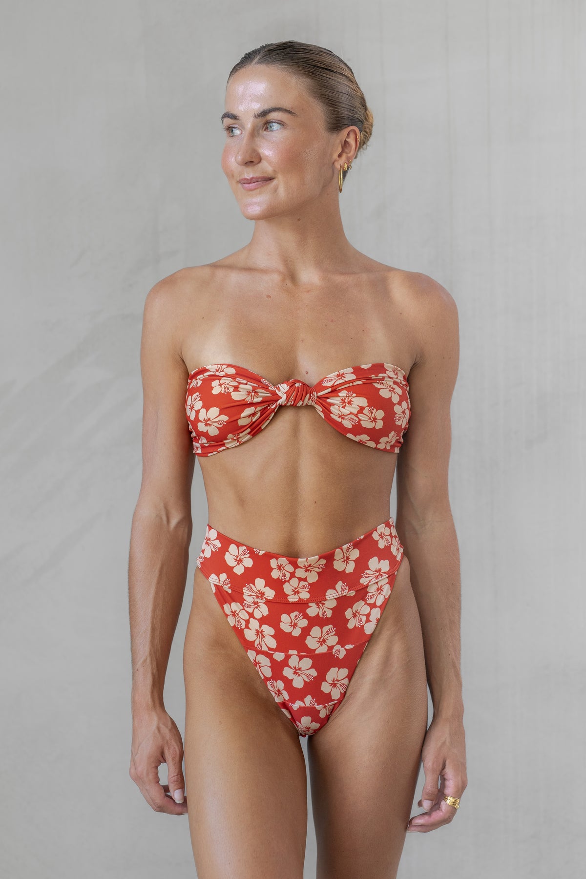 Woman wearing a red floral bikini against a plain background