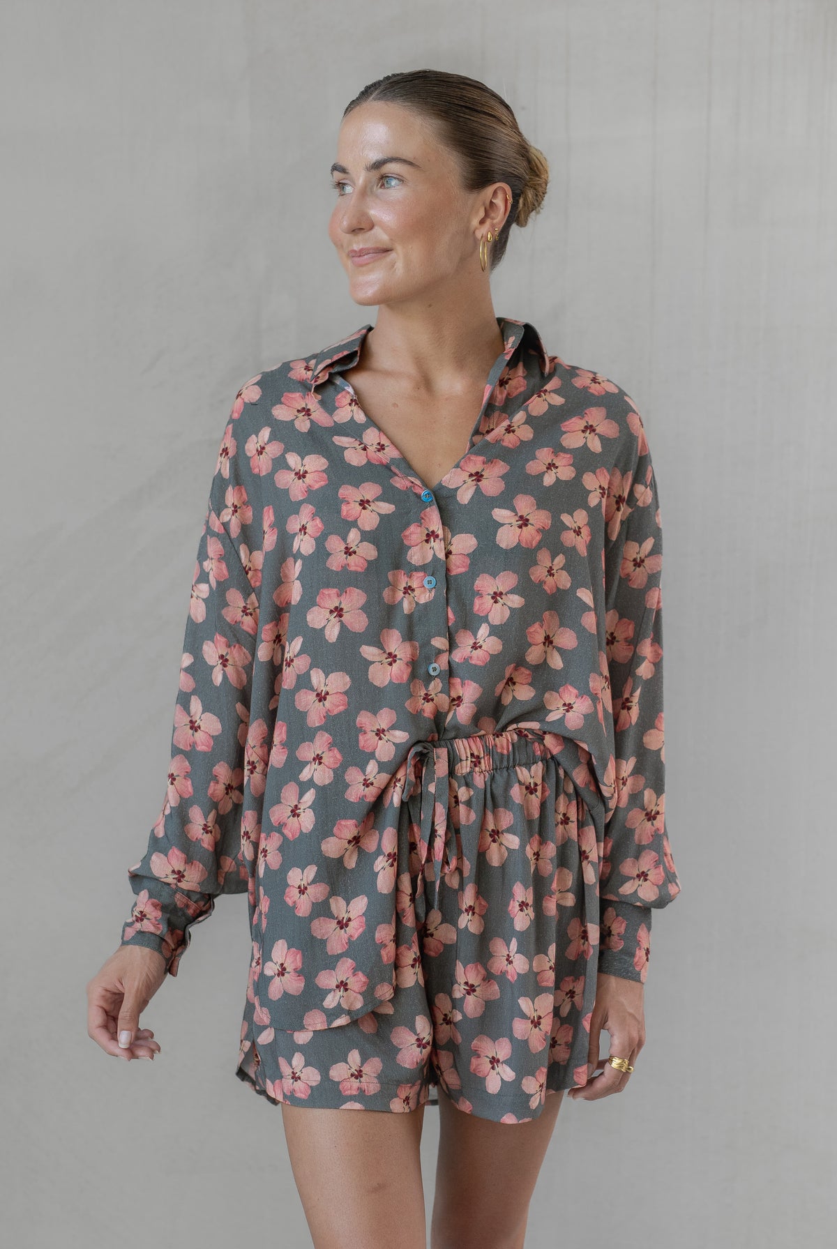Woman wearing a gray and pink floral shirt with matching shorts against a plain background
