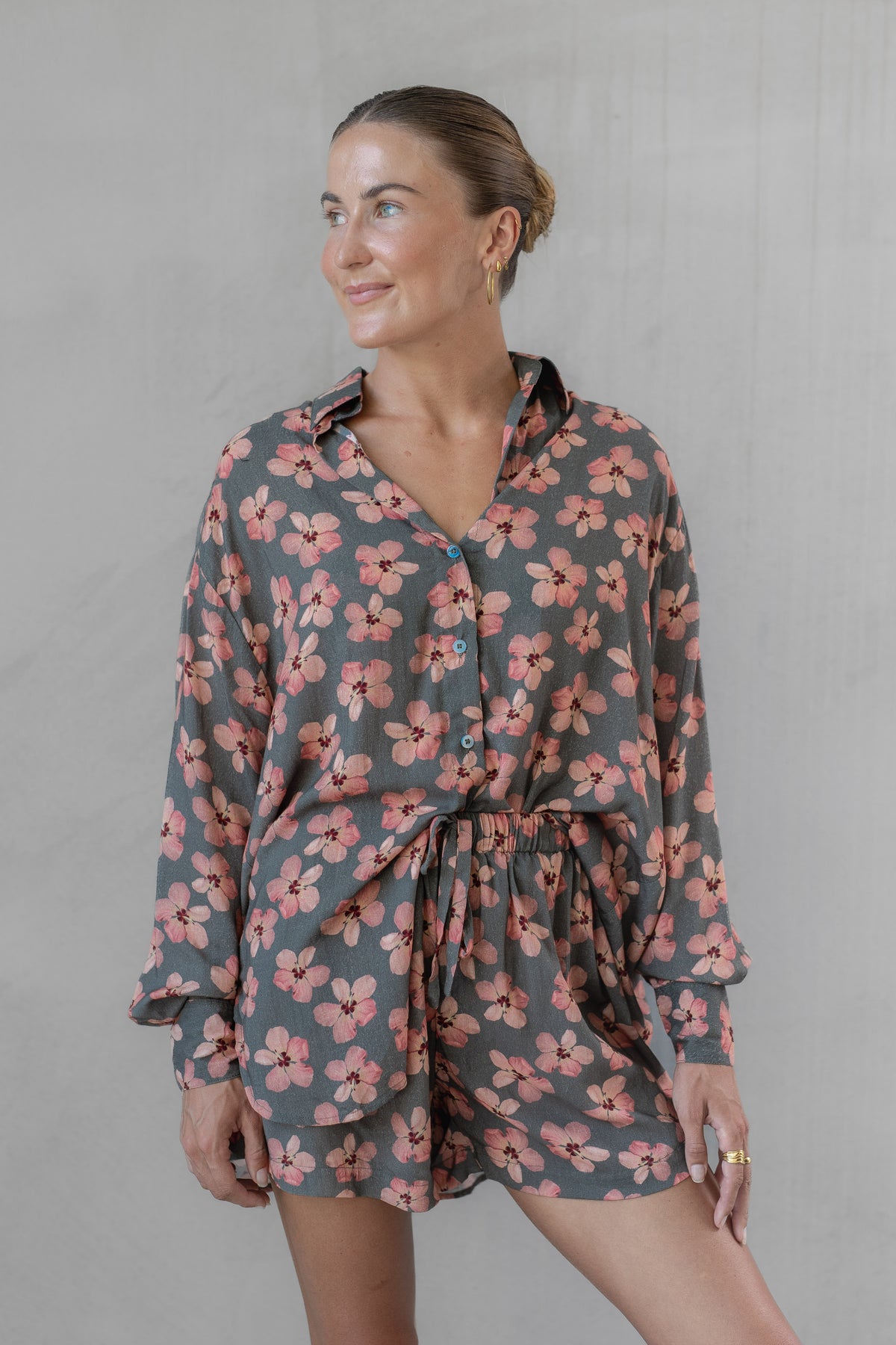 Woman wearing a gray and pink floral shirt with matching shorts against a plain background