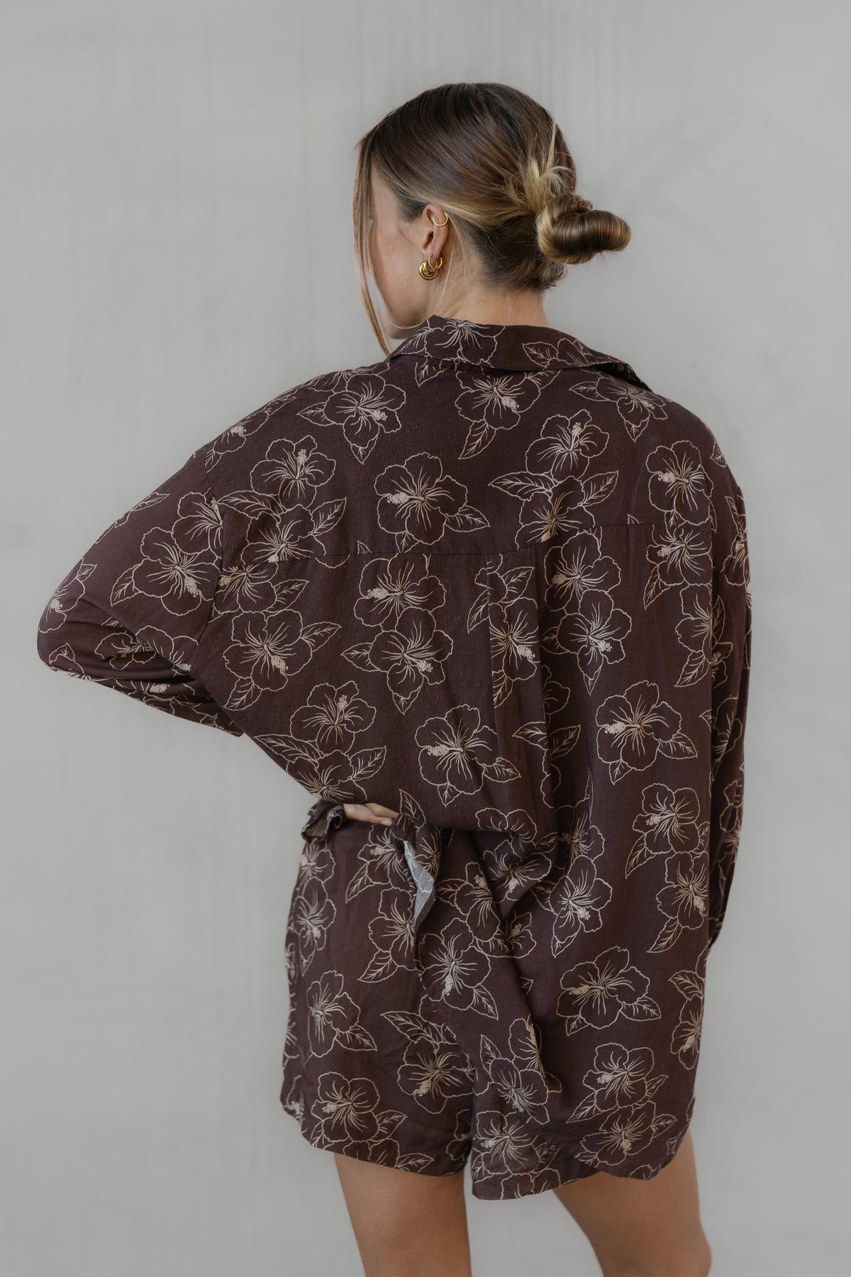 Person wearing a brown floral patterned shirt with matching shorts against a plain background