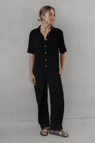 Person wearing a black outfit against a gray background