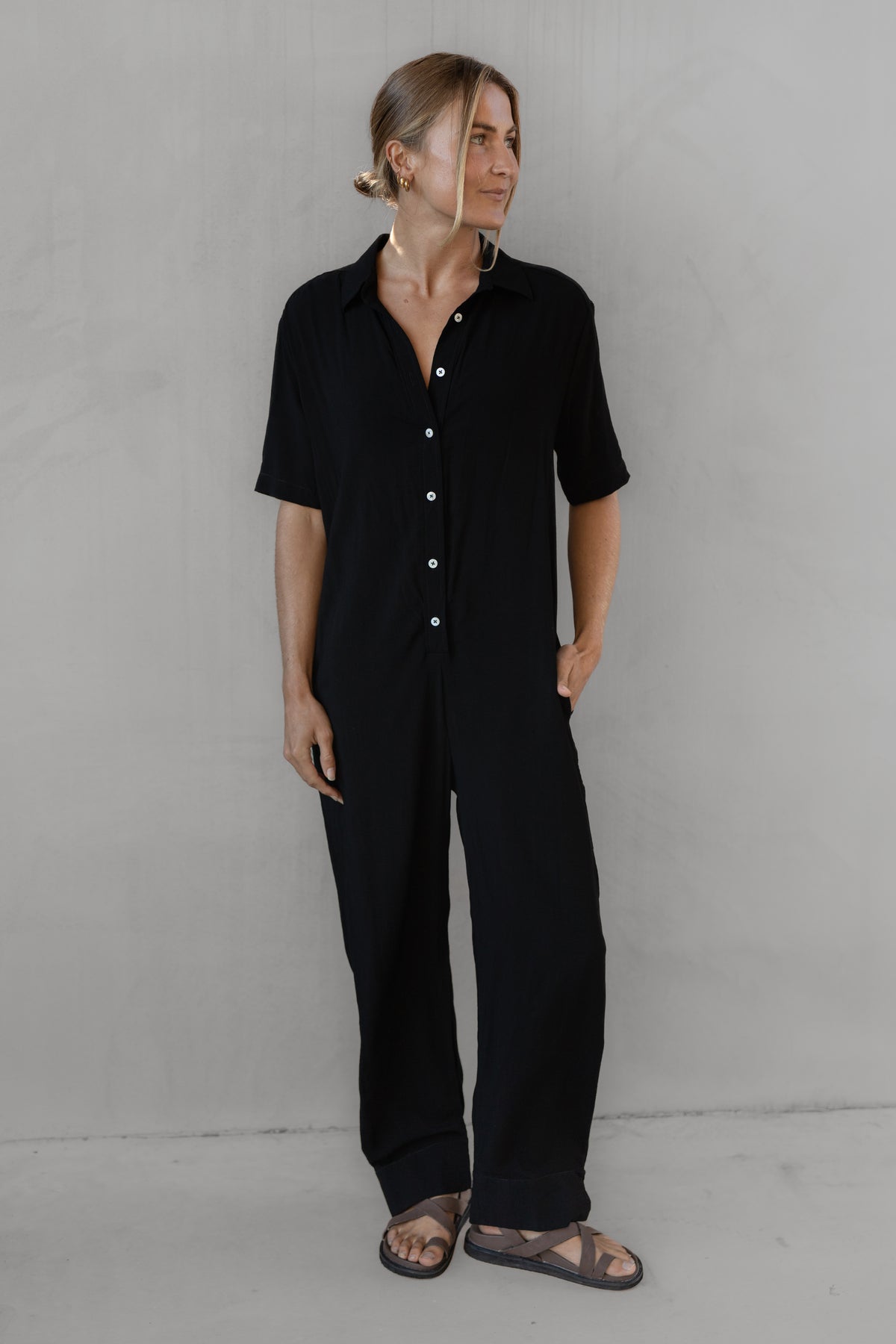 Person wearing a black outfit against a gray background