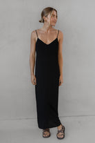 Woman wearing a long black dress with thin straps