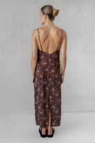 Woman wearing a brown slip dress with a subtle pattern on a plain background