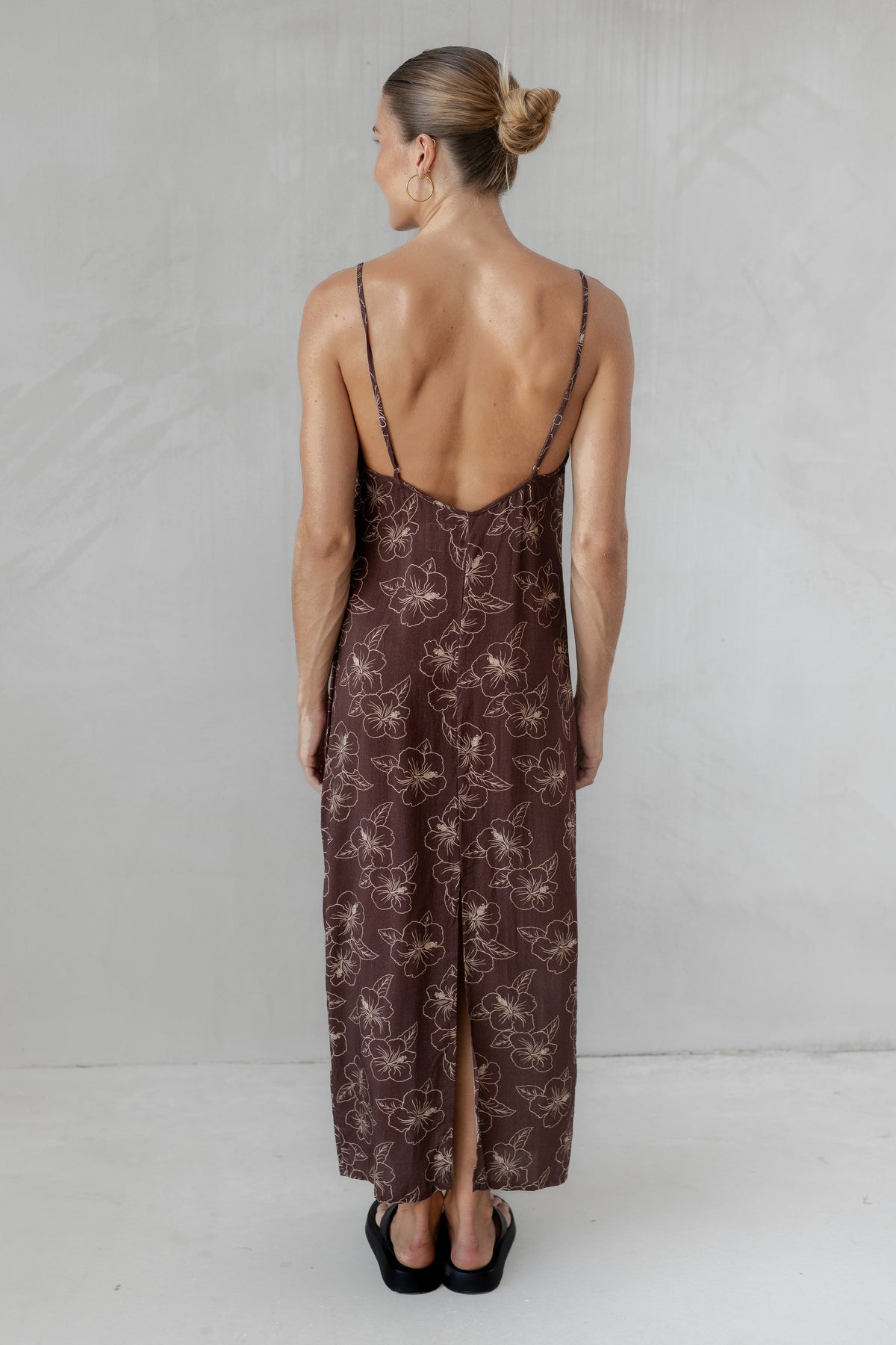 Woman wearing a brown slip dress with a subtle pattern on a plain background