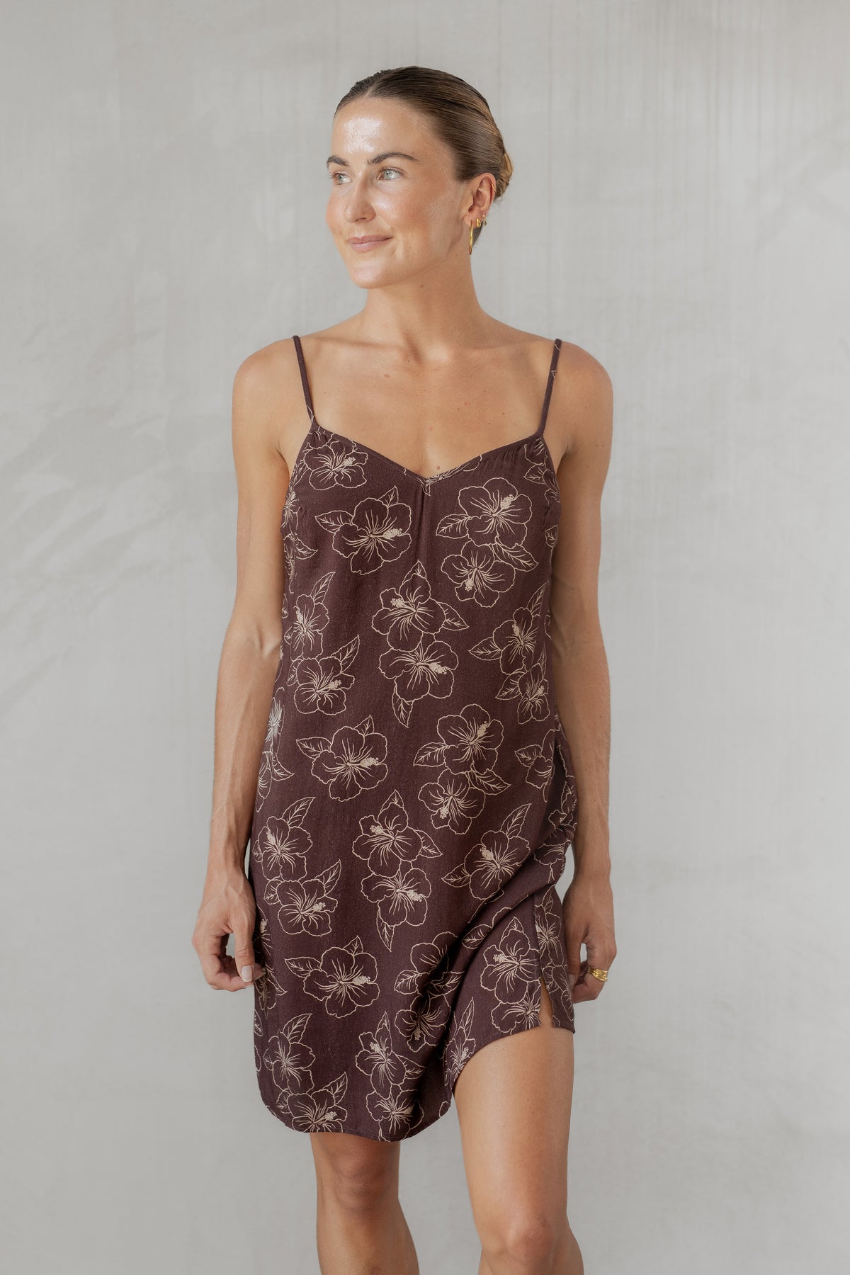 Woman wearing a brown floral slip dress against a plain background