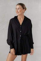 Woman wearing a black shirt with matching shorts against a neutral background