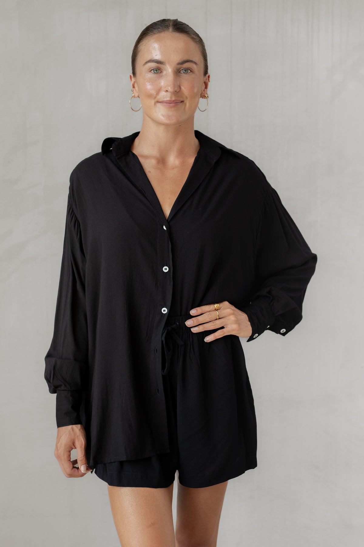 Woman wearing a black shirt with matching shorts on a plain background