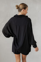 Woman wearing a black shirt with matching shorts on a plain background