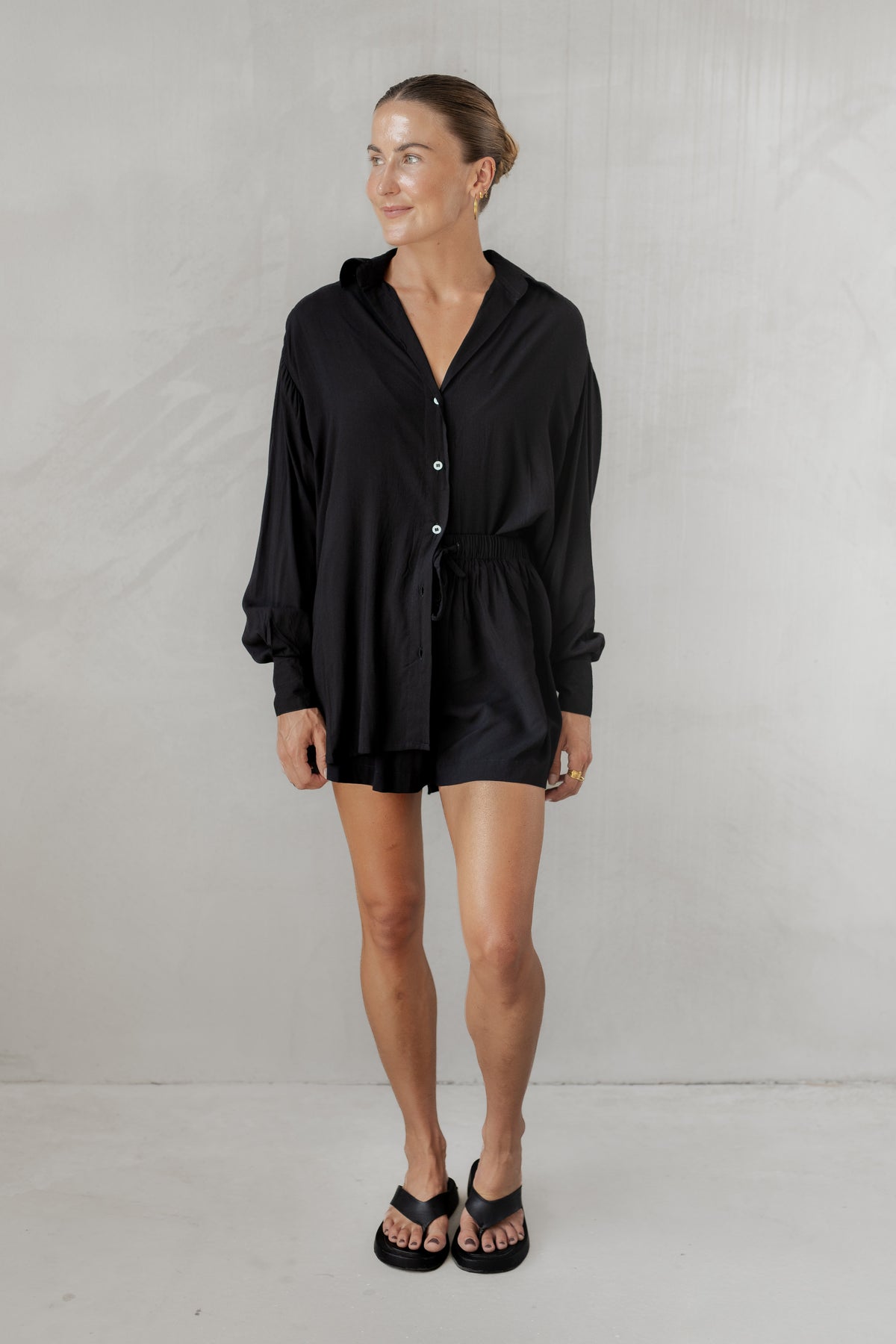 Woman wearing a black shirt with matching shorts against a plain background