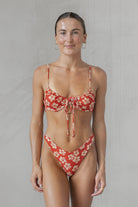 Woman wearing a red floral bikini against a plain background