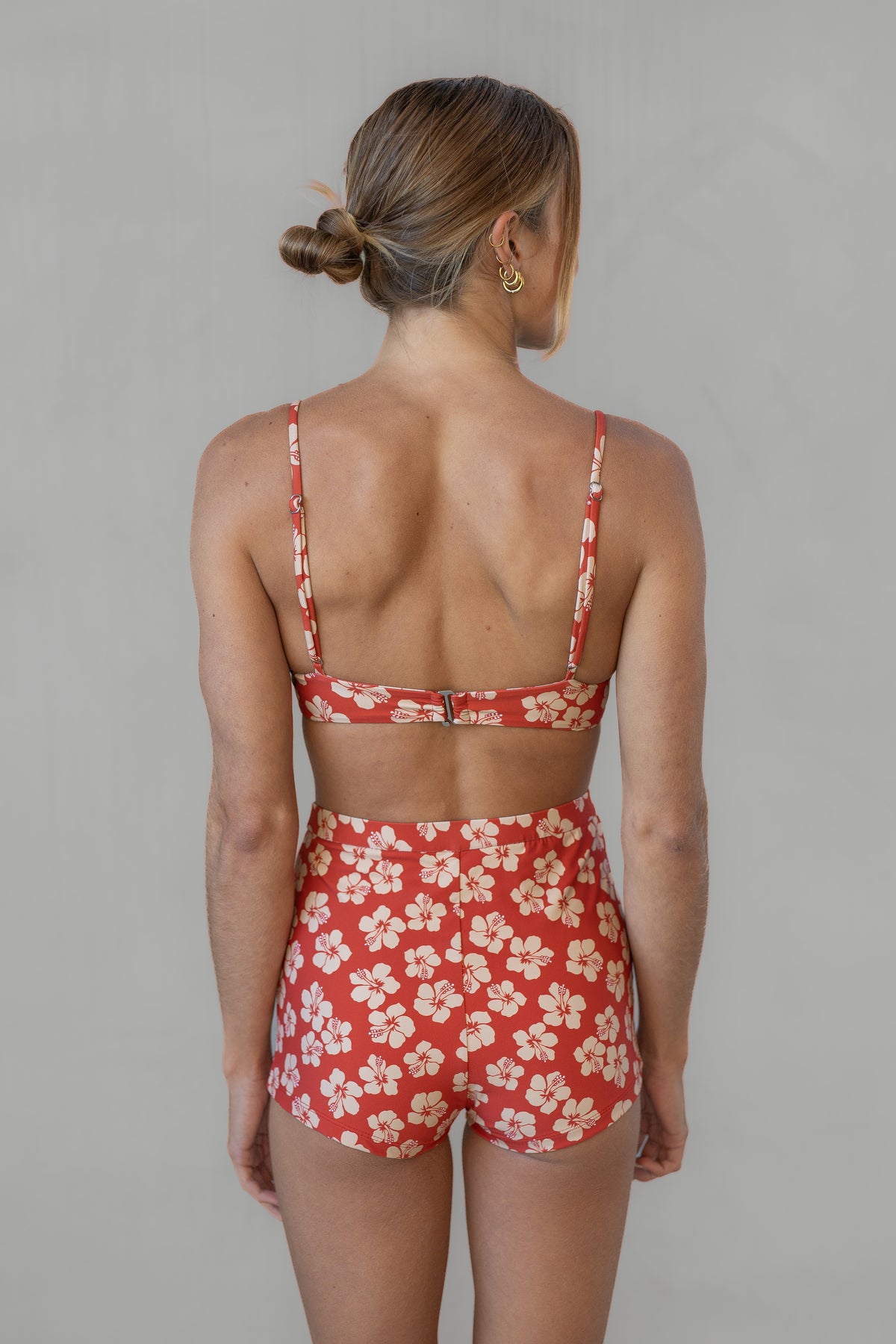 Woman wearing a red floral two-piece swimsuit against a gray background