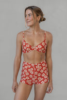 Woman wearing a red floral two-piece swimsuit against a plain background