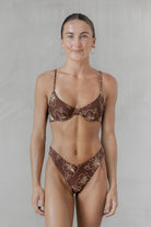 Woman wearing a brown floral bikini against a plain background