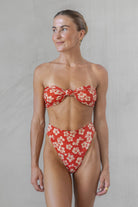 Woman wearing a red floral bikini against a plain background