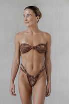 Woman wearing a brown patterned bikini against a neutral background