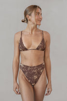 Woman wearing a brown floral bikini set against a plain background
