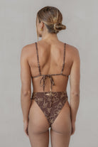 Woman wearing a brown floral bikini against a neutral background
