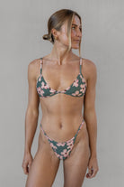 Woman wearing a gray and pink floral bikini against a plain background
