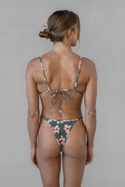 Woman wearing a gray and pink floral bikini against a neutral background