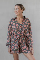 Woman wearing a gray and pink floral shirt with matching shorts against a plain background