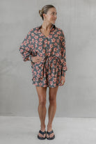 Woman wearing a gray and pink floral shirt with matching shorts against a plain background