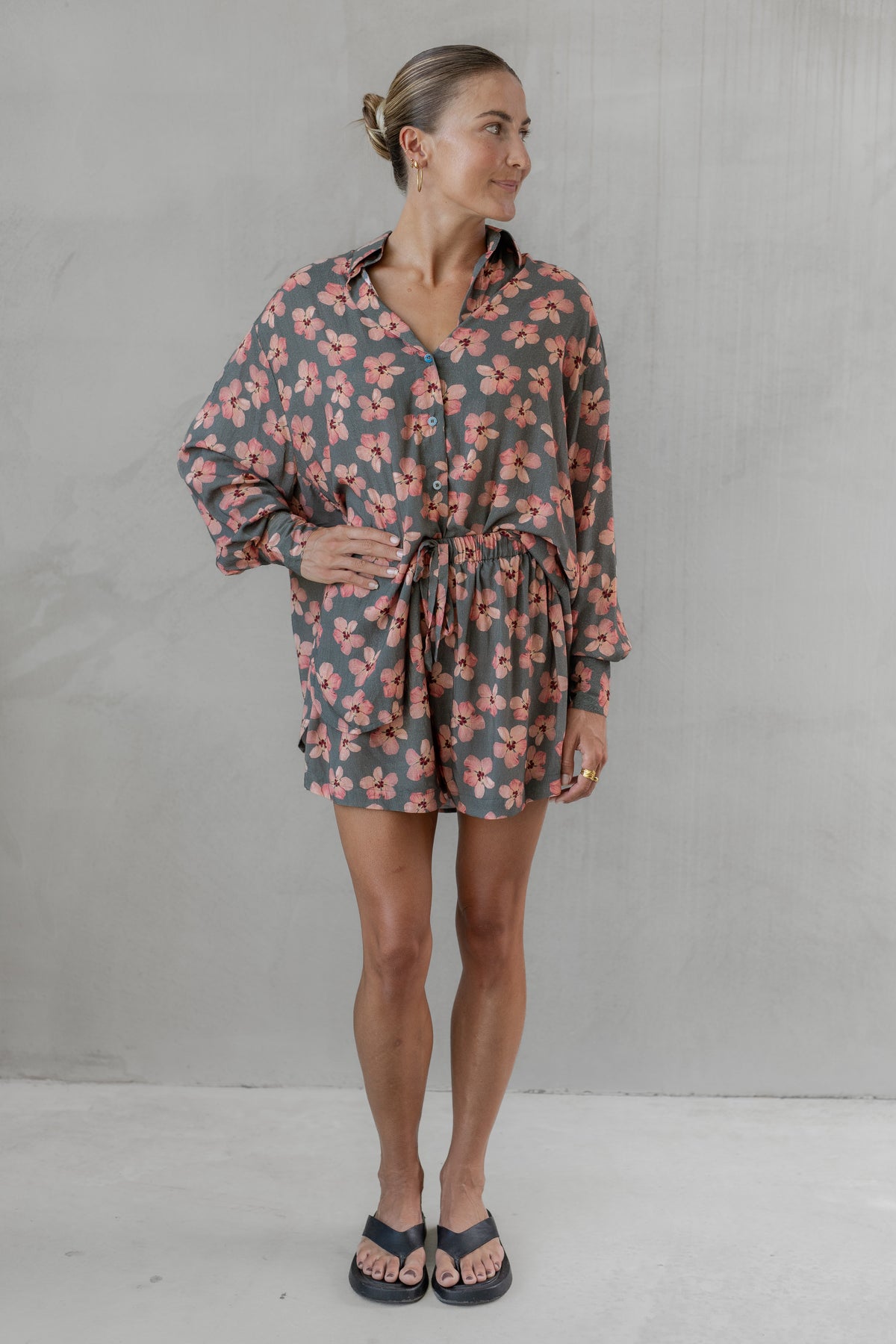 Woman wearing a gray and pink floral shirt with matching shorts against a plain background